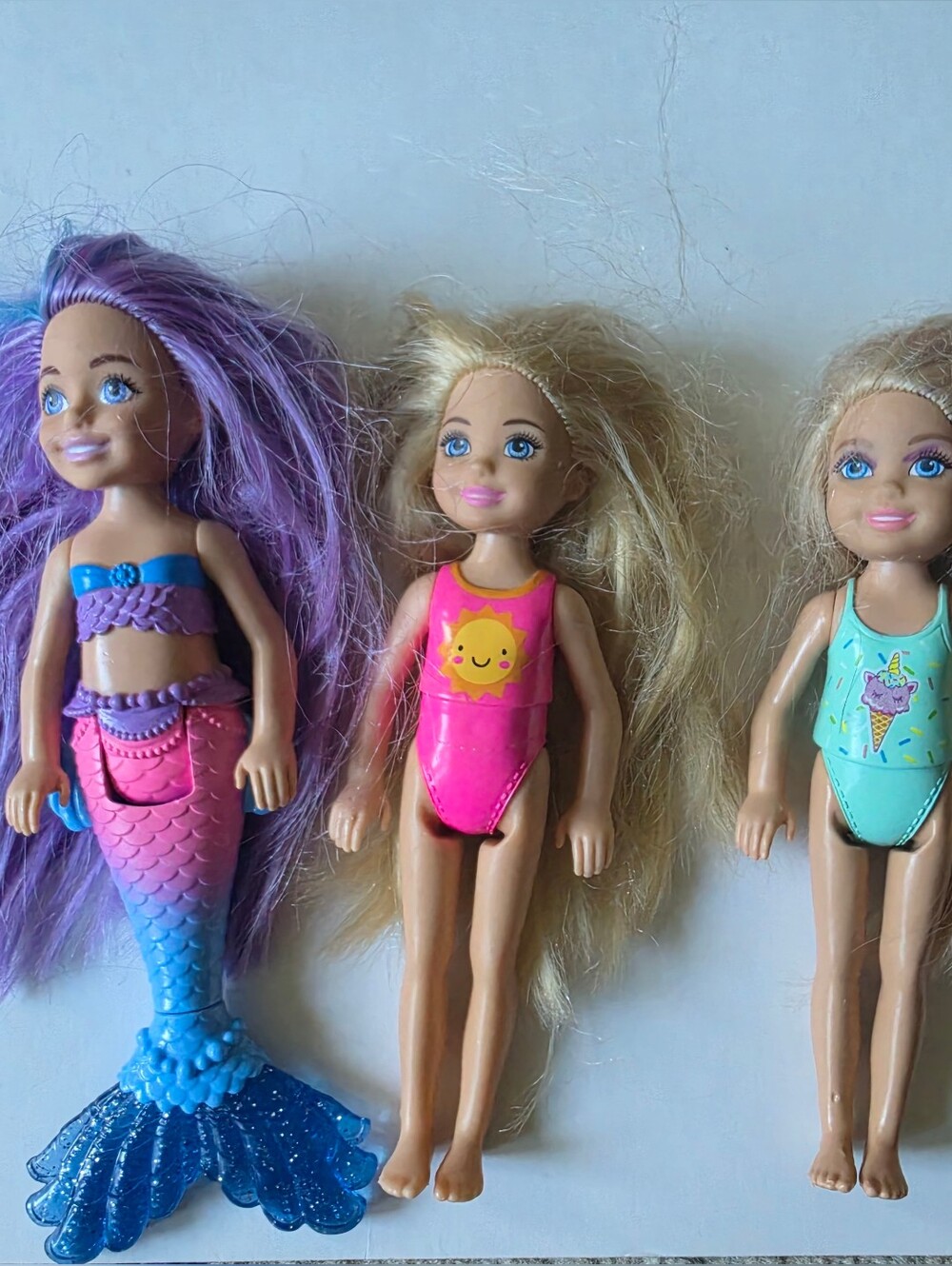 four small Mattel Barbie Chelsea size fashion and mermaid dolls.